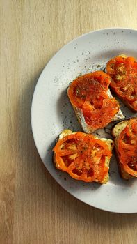 Appetizing tomato bruschetta with herbs served on a white plate, showcasing simple food aesthetics.