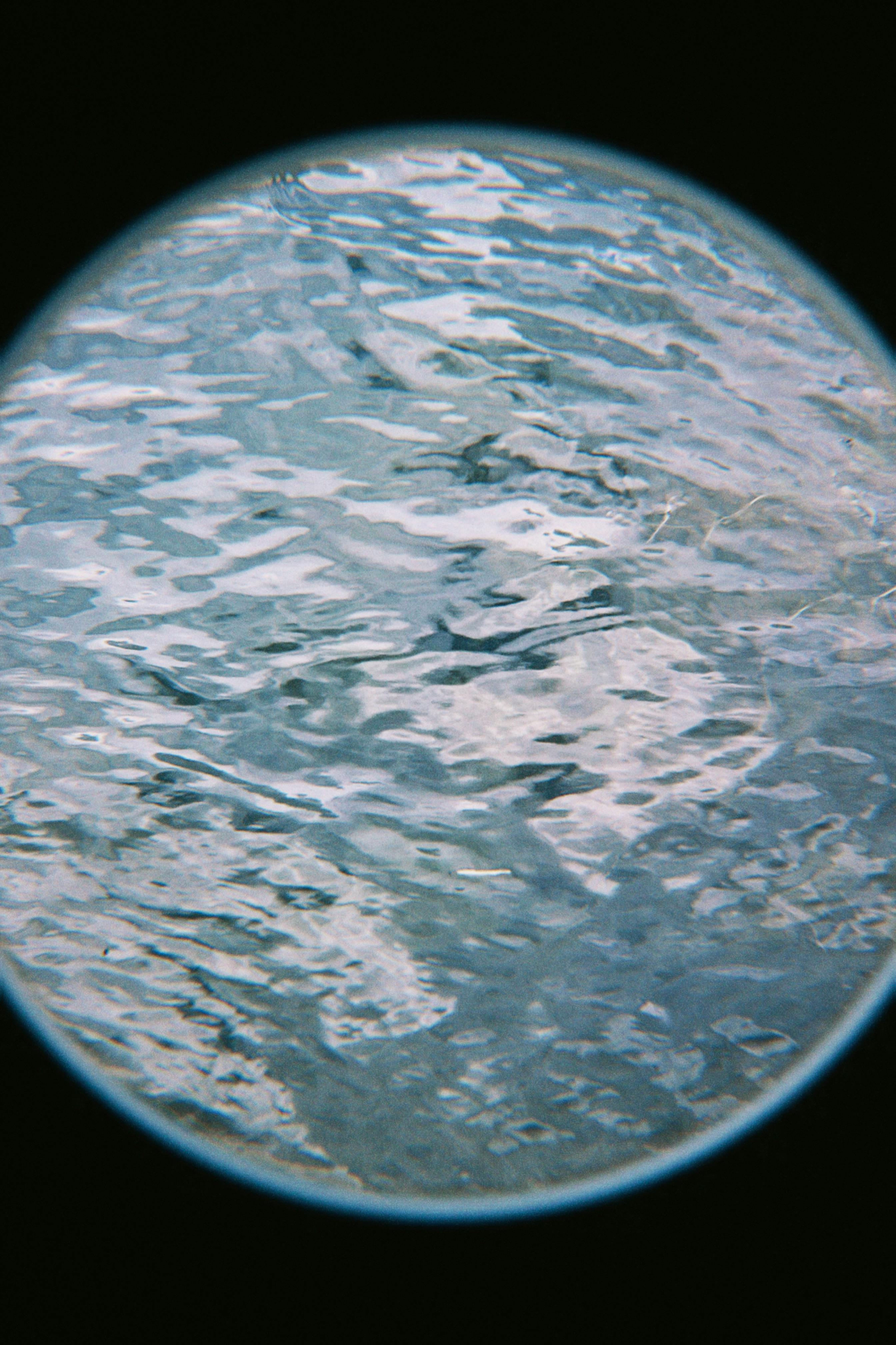 Abstract texture of a water surface viewed through a circular frame, creating a unique visual effect.