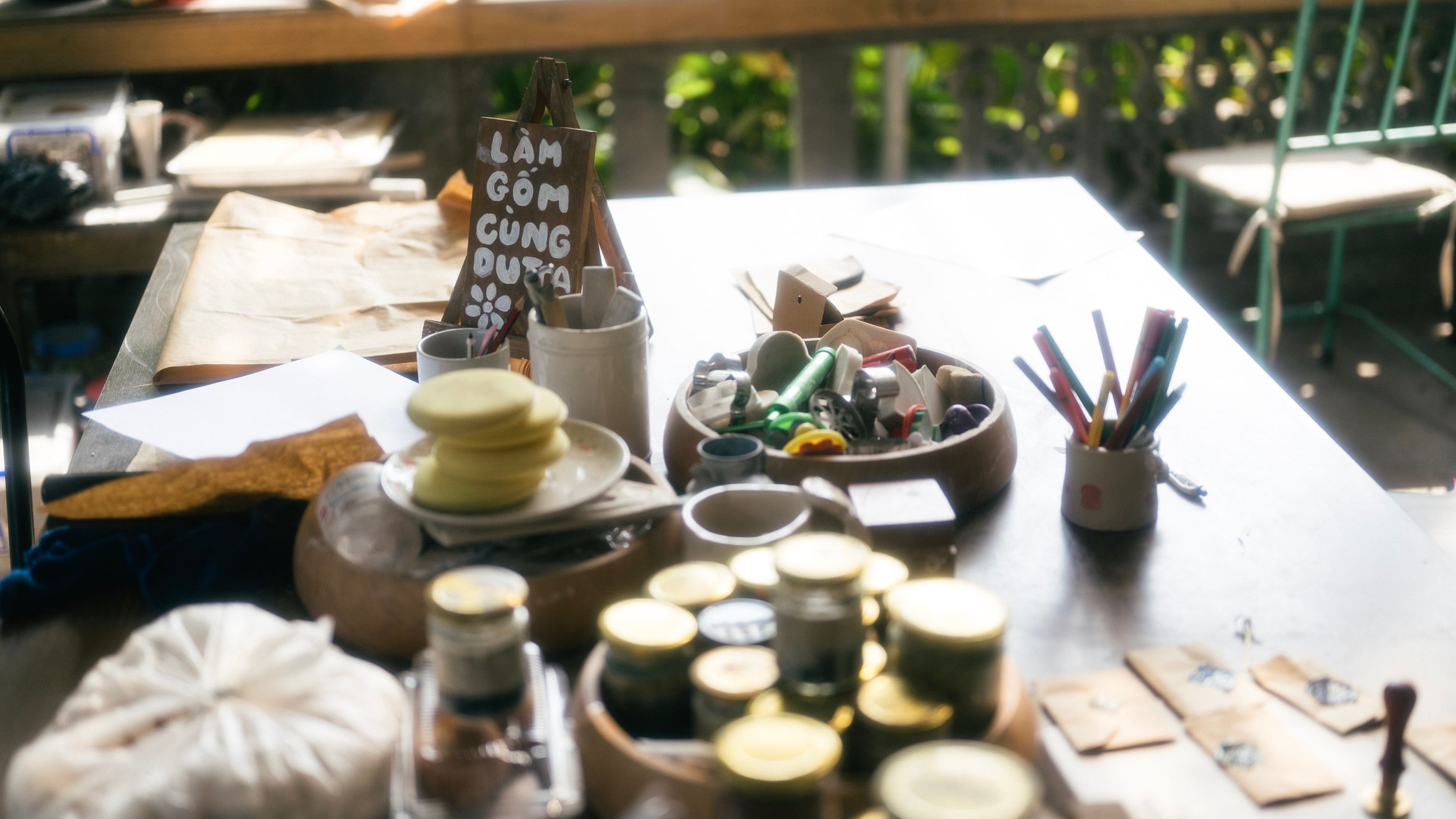 Cozy craft table with art supplies and handwritten sign in a sunlit workspace, Lạng Sơn.
