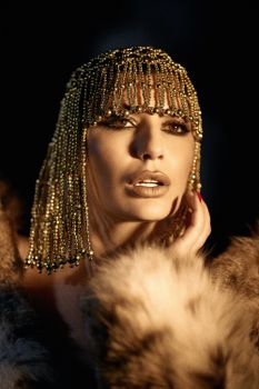 Elegant portrait of a woman wearing a gold beaded headdress with a luxurious fur coat.