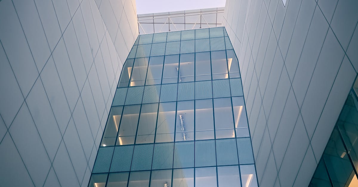 Photo by Matthew Jesús A striking shot of a modern glass building facade captured from below, with reflections at sunrise.