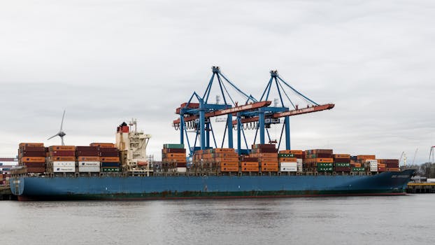A container ship docked at Hamburg port surrounded by cranes and shipping containers.