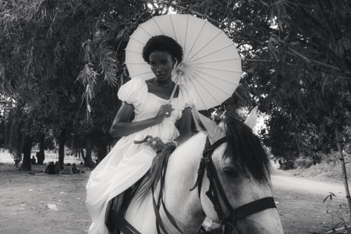 Free Elegant woman in vintage dress riding a horse, holding a parasol, black and white image. Stock Photo