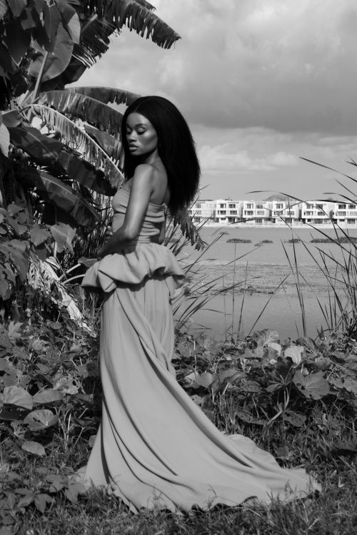 Free Striking black and white portrait of an elegant woman standing by water with a natural backdrop. Stock Photo