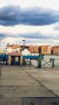 A scenic view of Alexandria harbor with boats and a worker in the early morning light.