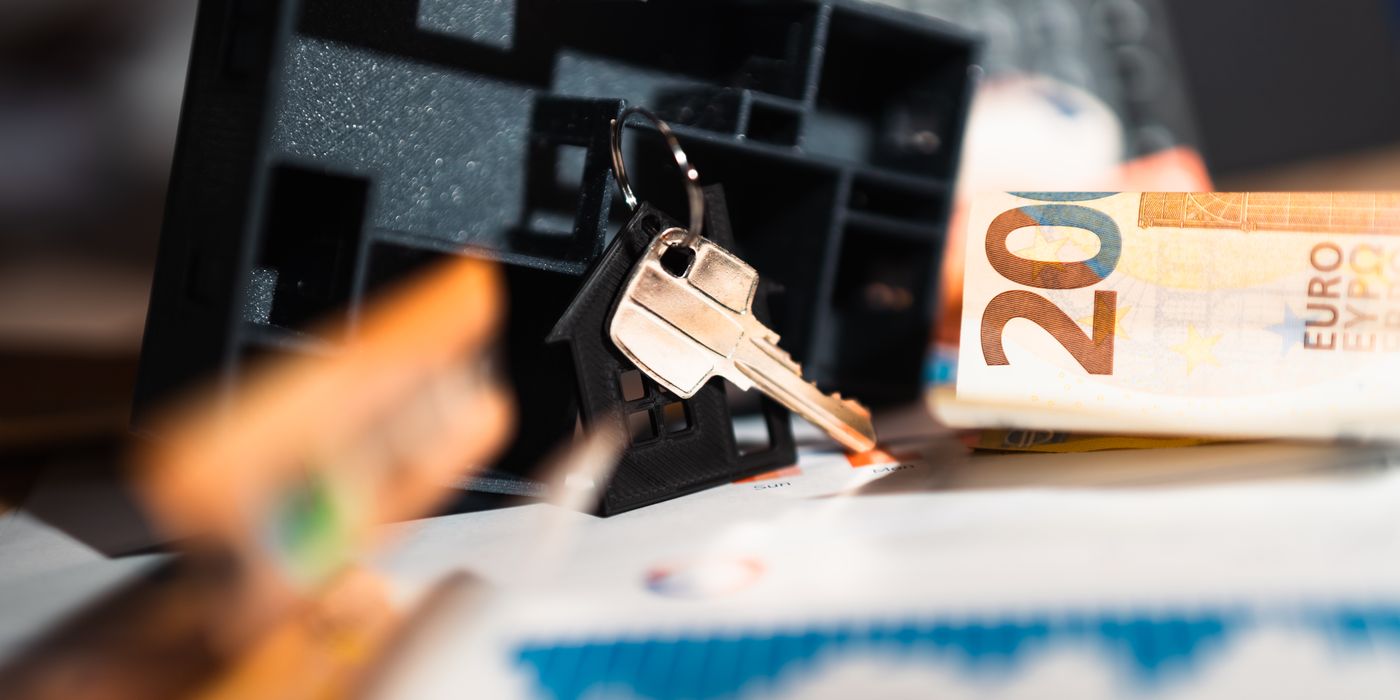 Keys with a house model, Euro bills, and charts suggesting real estate and financial themes.