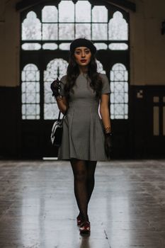 Stylish model in vintage fashion poses indoors with İstanbul's historic architecture as backdrop.