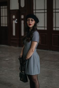 Stylish woman in vintage attire posing indoors with classic decor.