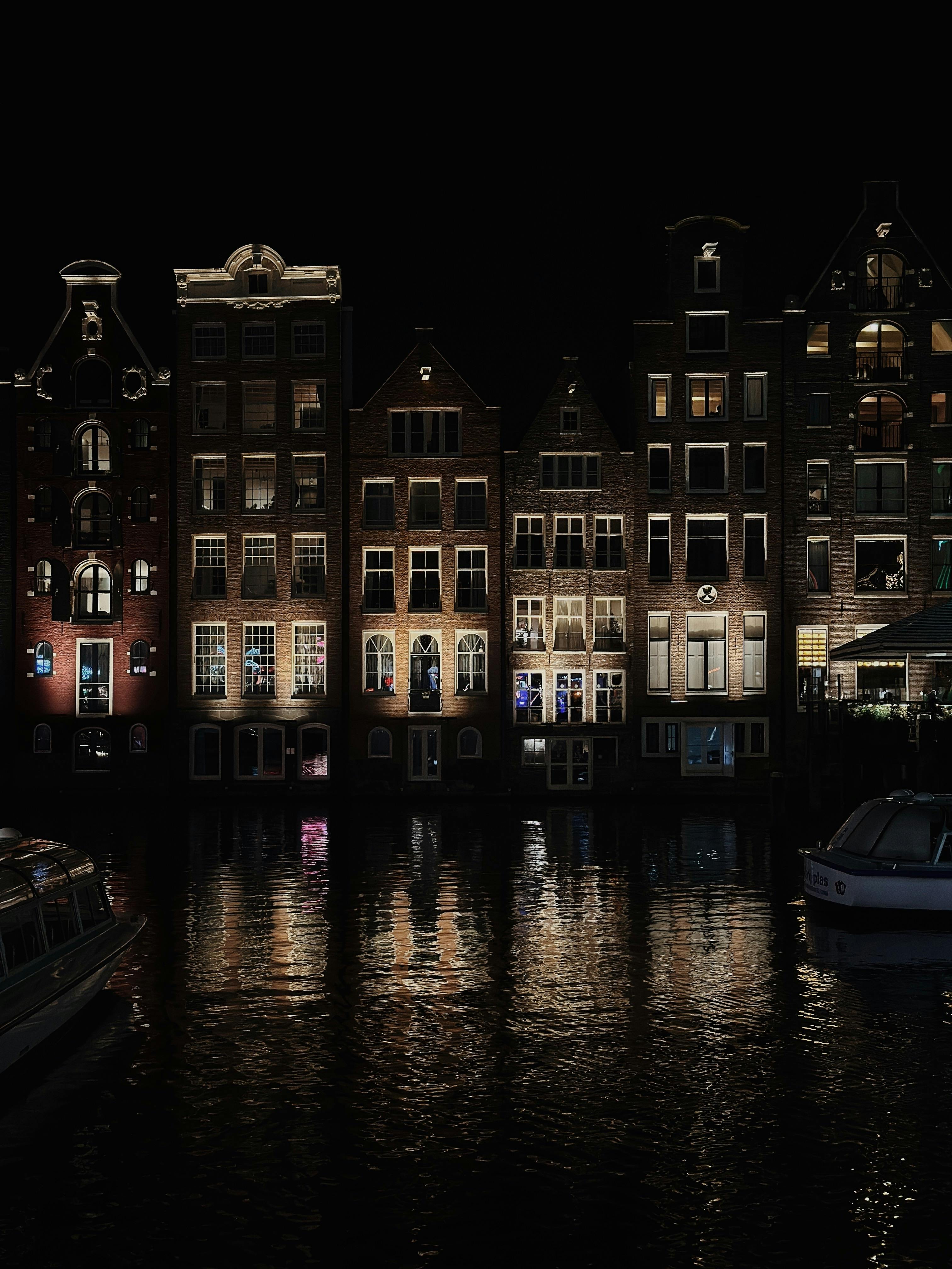 Night view of Amsterdam canal houses reflected in still water
