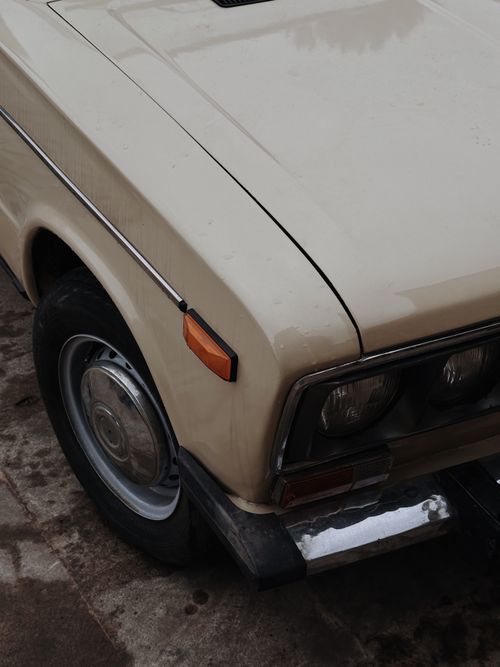 Free Close-up of a vintage beige car highlighting its headlight and chrome details, evoking retro vibes. Stock Photo