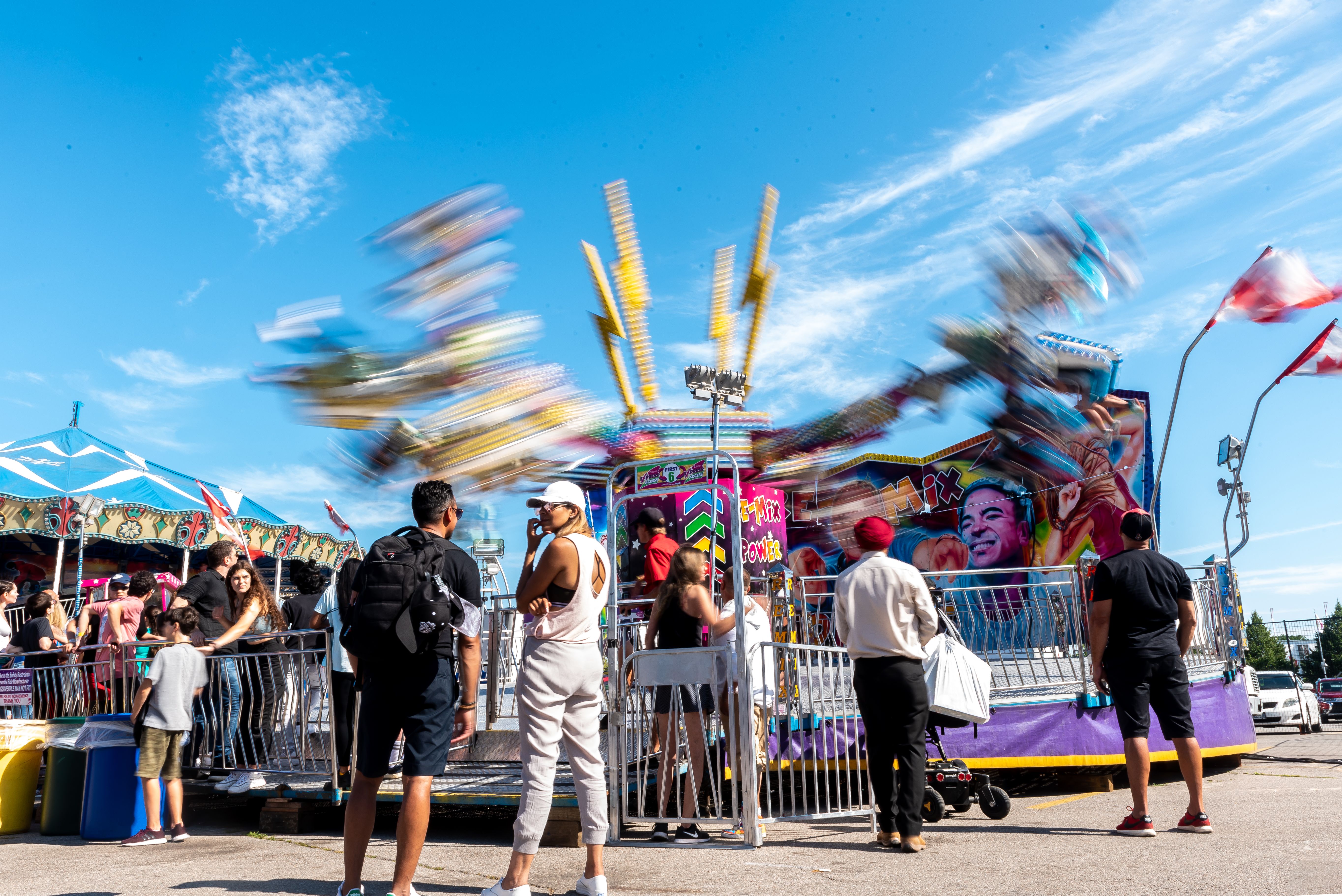 Vibrant amusement park scene with spinning ride and diverse crowd enjoying a sunny day.