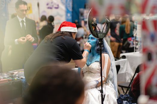 Cosplayer getting vibrant blue makeup applied at a convention in San José, Costa Rica.