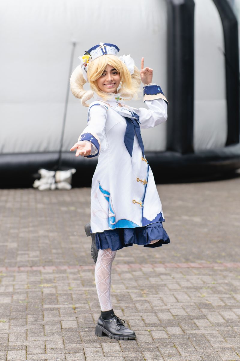 A cosplayer dressed in a detailed anime costume poses outdoors at an anime convention in San José, Costa Rica.