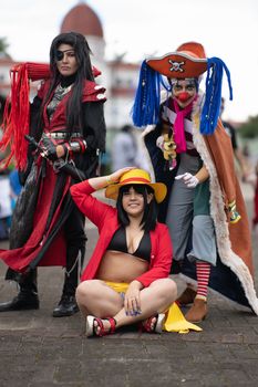 Cosplayers dressed in anime attire pose creatively at an outdoor convention in San José, Costa Rica.