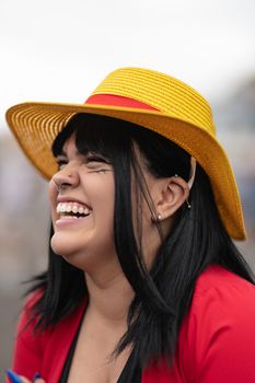 Joyful woman in cosplay attire with straw hat, captured during a lively anime festival.
