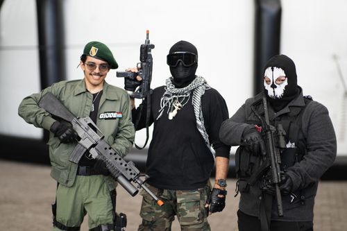Free Three adults in cosplay costumes with weapons at an outdoor event. Stock Photo