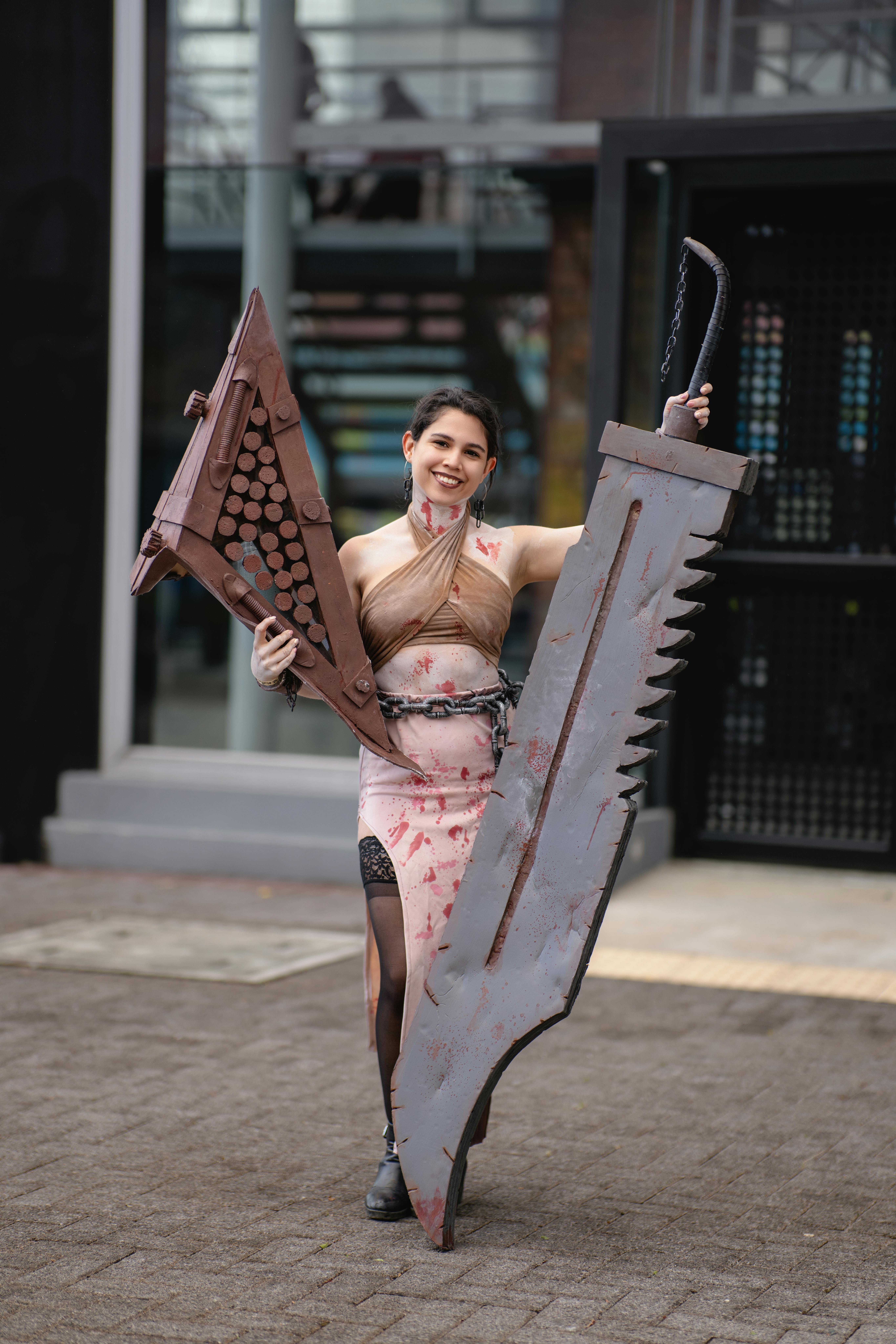 A cosplayer holding two large swords at an outdoor anime event in San José, Costa Rica.