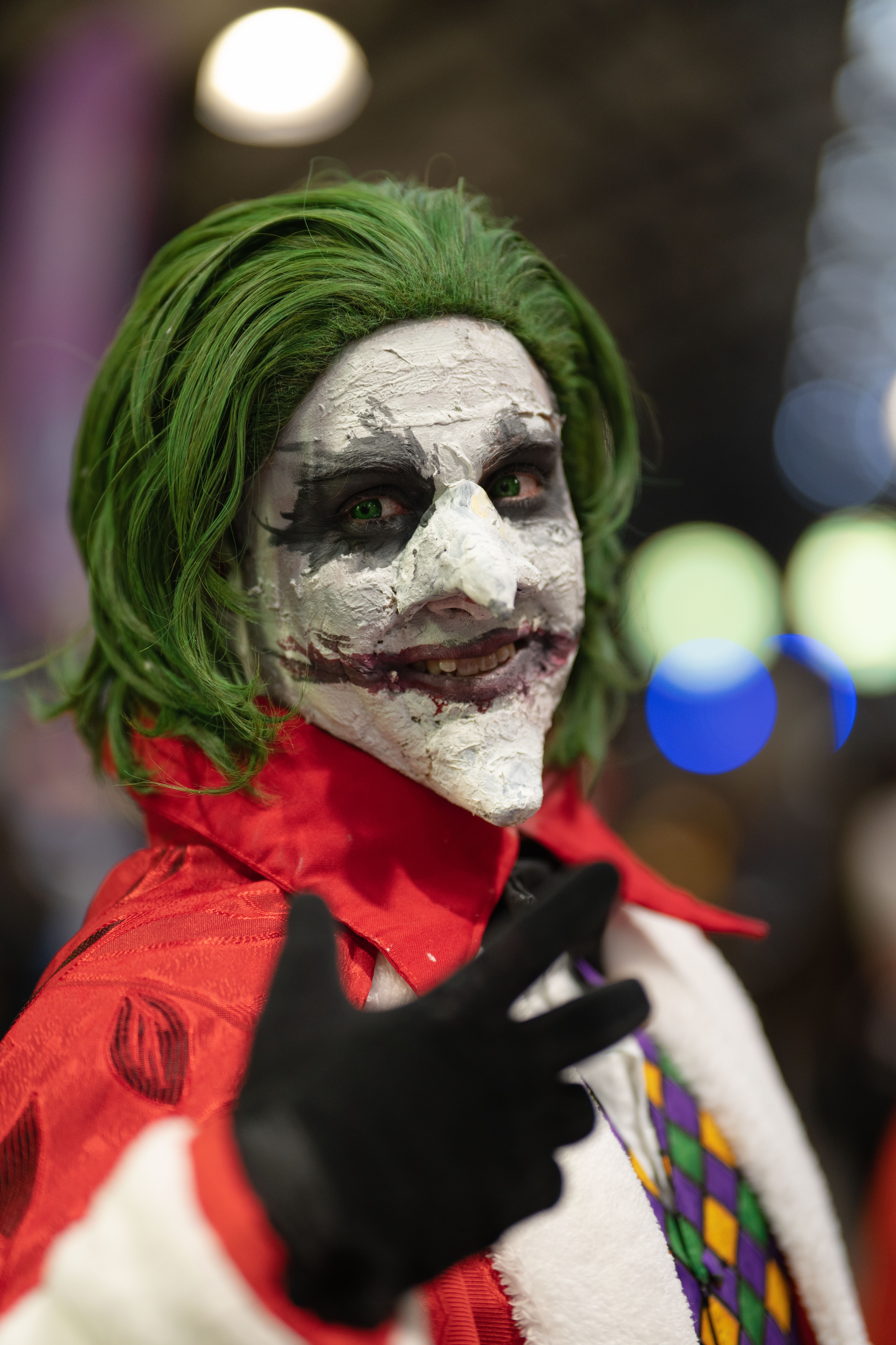Close-up of Joker cosplay at an anime convention in San José, Costa Rica, showcasing vibrant makeup and costume.