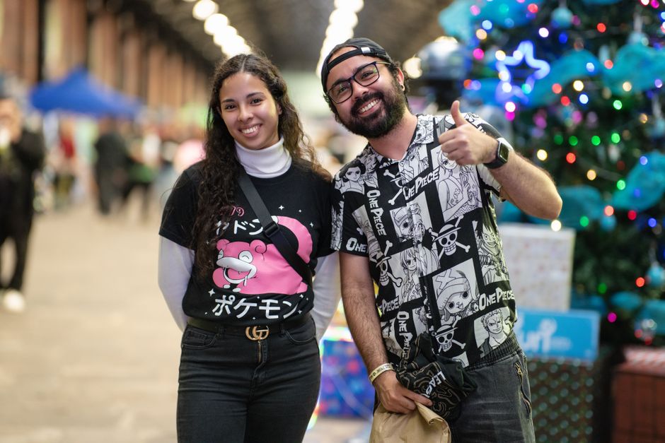 Two adults enjoying an anime and cosplay event in San José with festive lights.