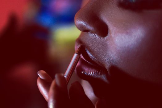 An artistic close-up shot focusing on makeup application with a brush on lips.