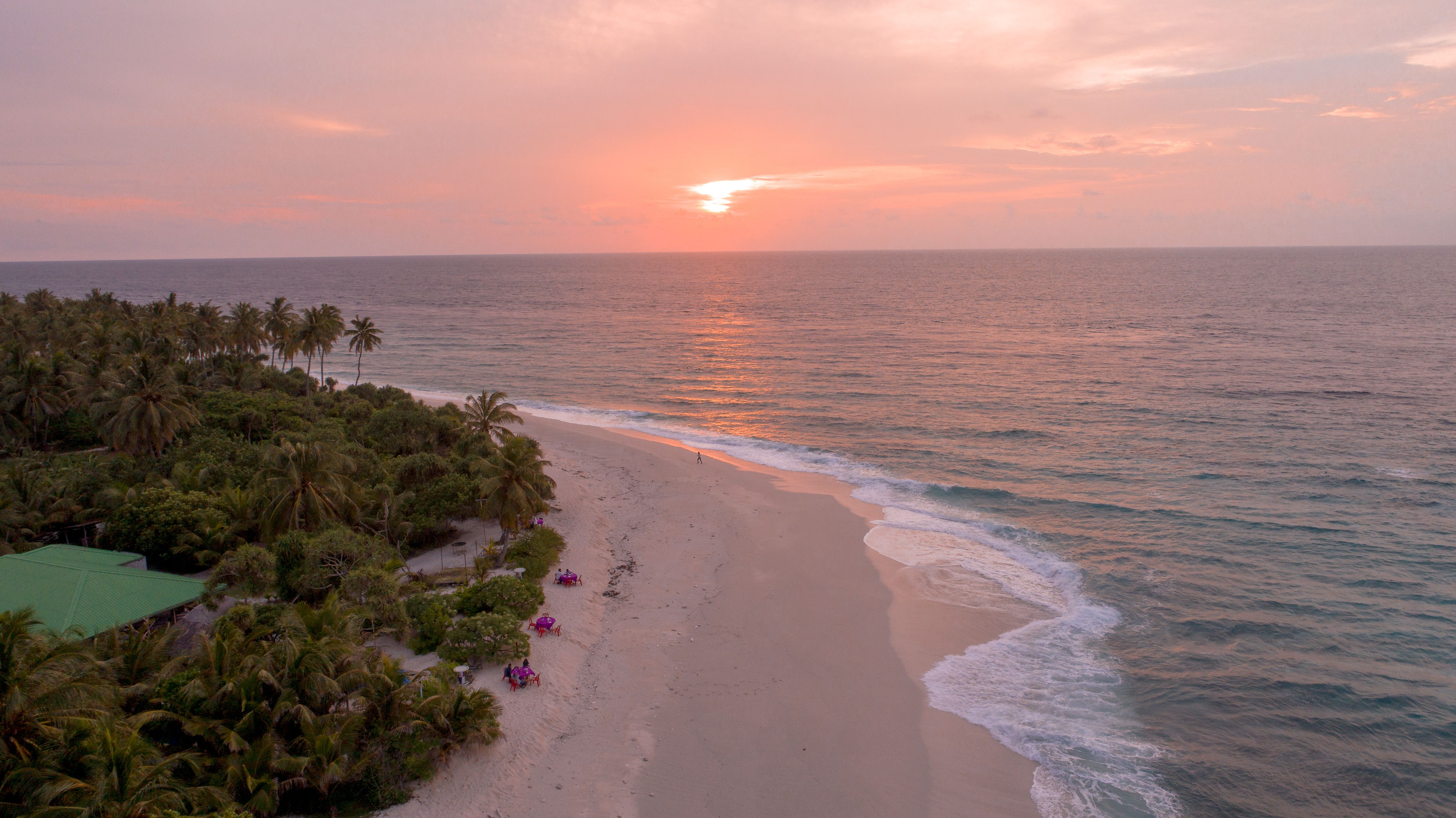 Aerial view of a tranquil Maldivian beach during a stunning sunset.