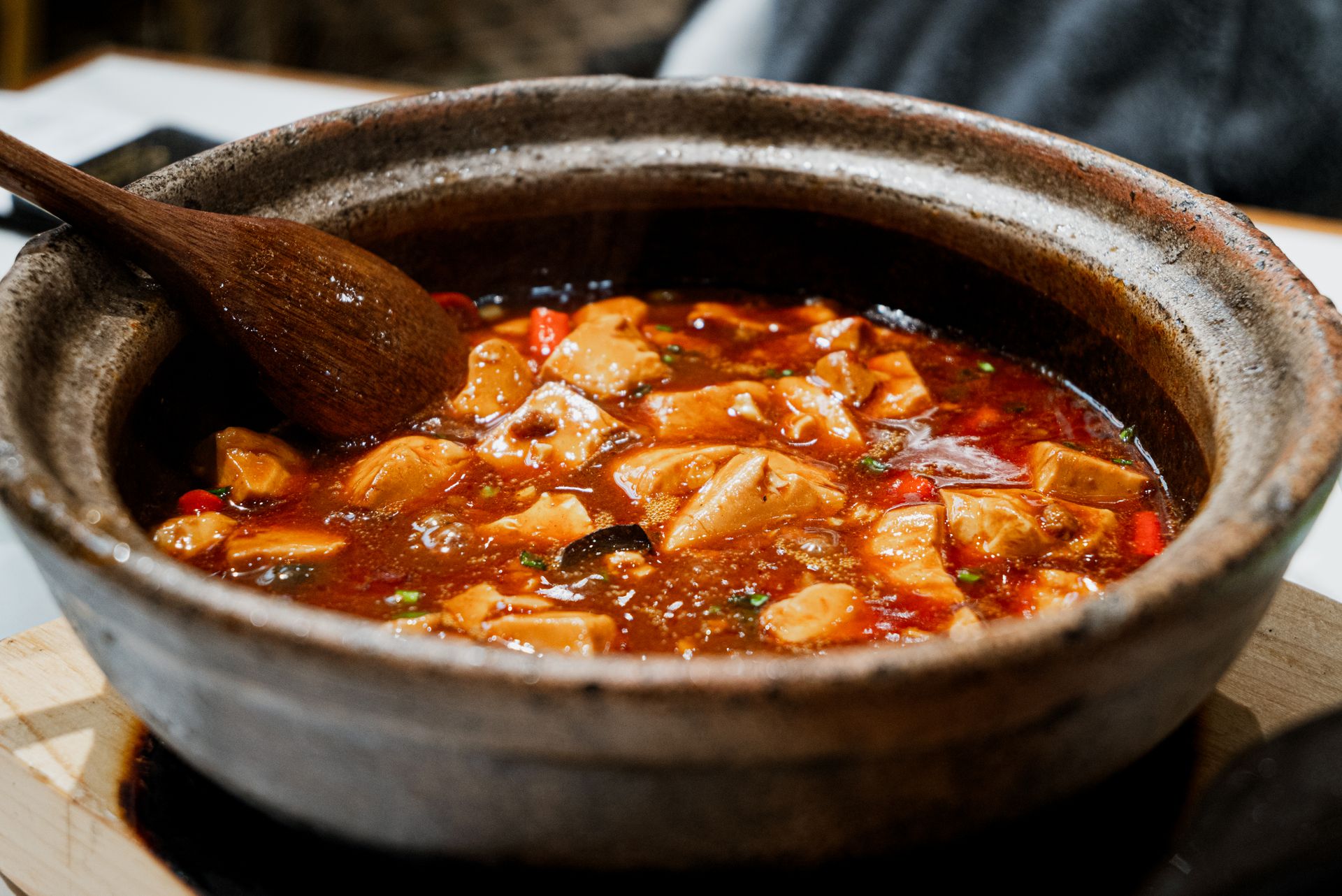 Close-up of a flavorful tofu stew simmering in a rustic pot with a wooden spoon.