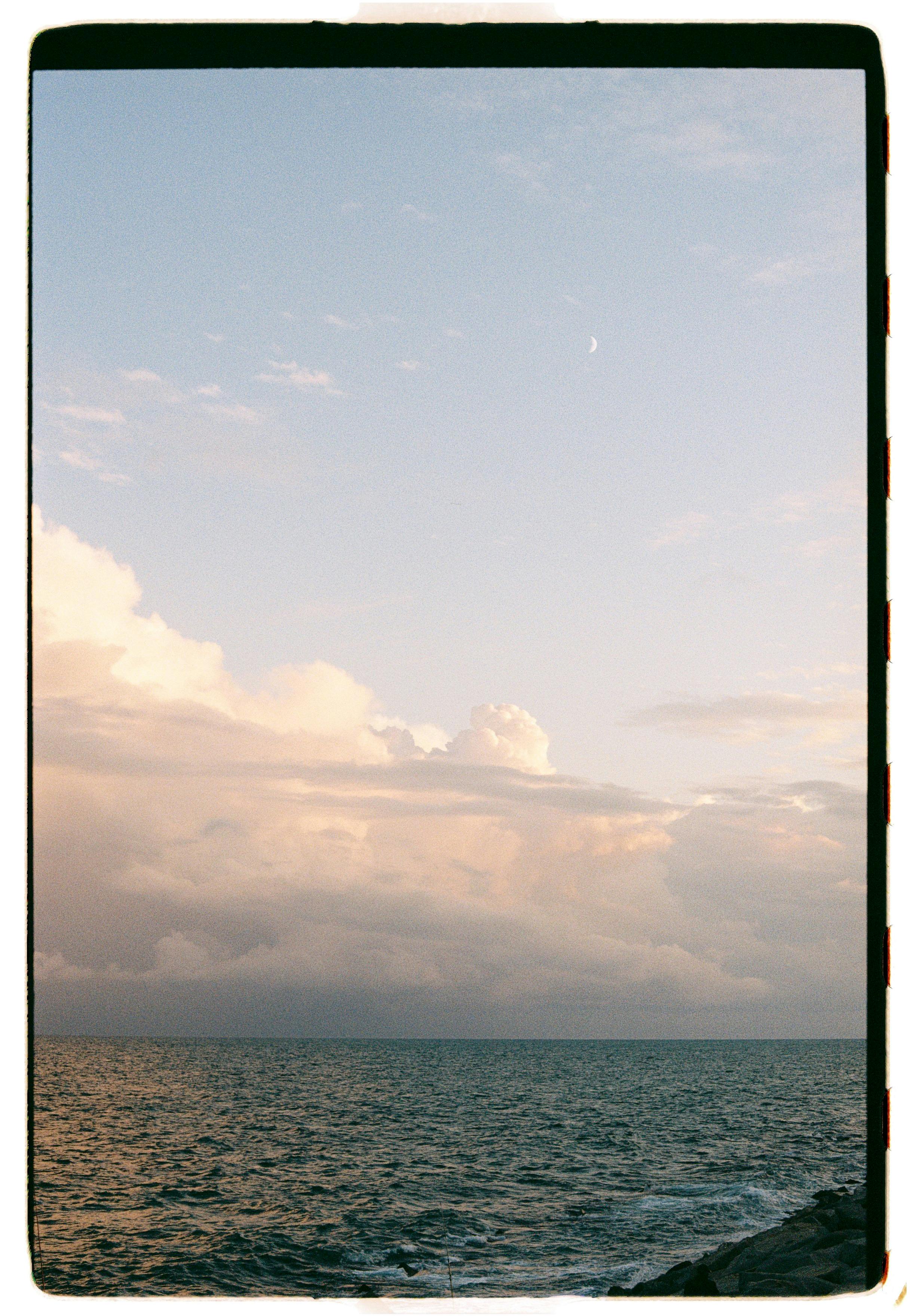 Peaceful ocean scene with soft clouds at dusk, creating a tranquil and serene atmosphere.