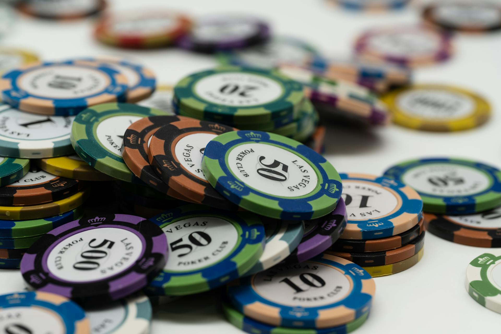 Stacked Las Vegas poker chips showcasing different denominations on a white surface.