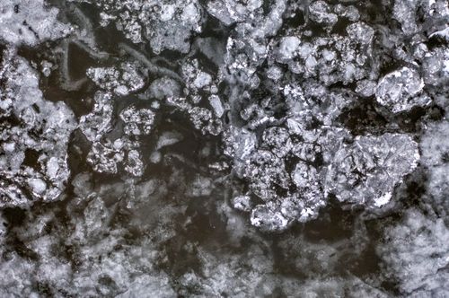 Free Detailed aerial shot of a frozen river with cracked ice patterns in winter. Stock Photo
