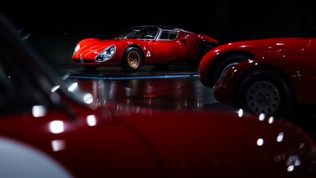 Showcasing a classic Alfa Romeo racing car in a dimly lit museum setting.