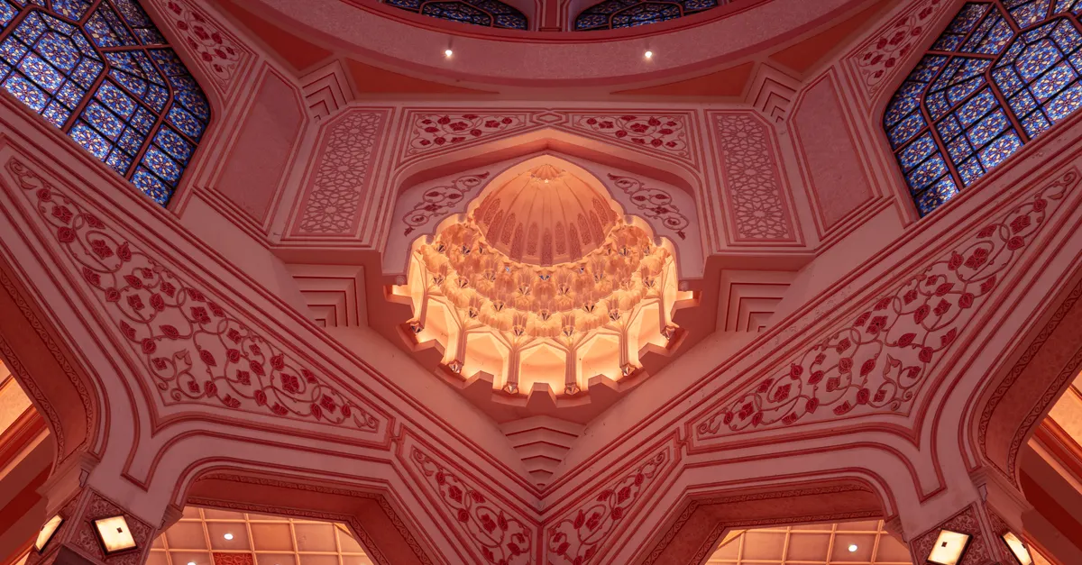 La mosquée Putra, ou mosquée rose, avec son dôme rose et ses minarets élancés se reflétant dans le lac de Putrajaya