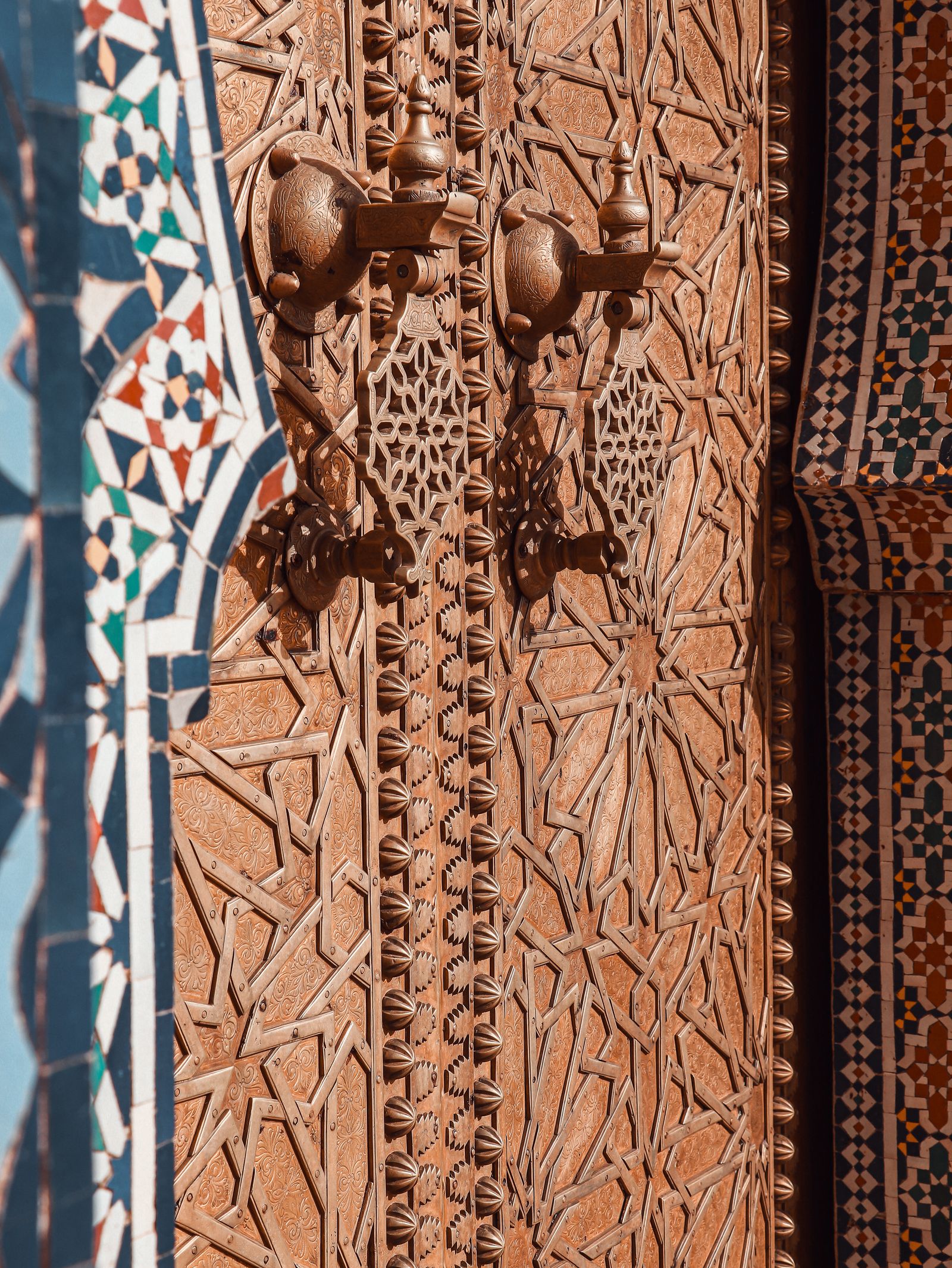 Porte traditionnelle marocaine en bois sculpté avec ferrures en cuivre, médina