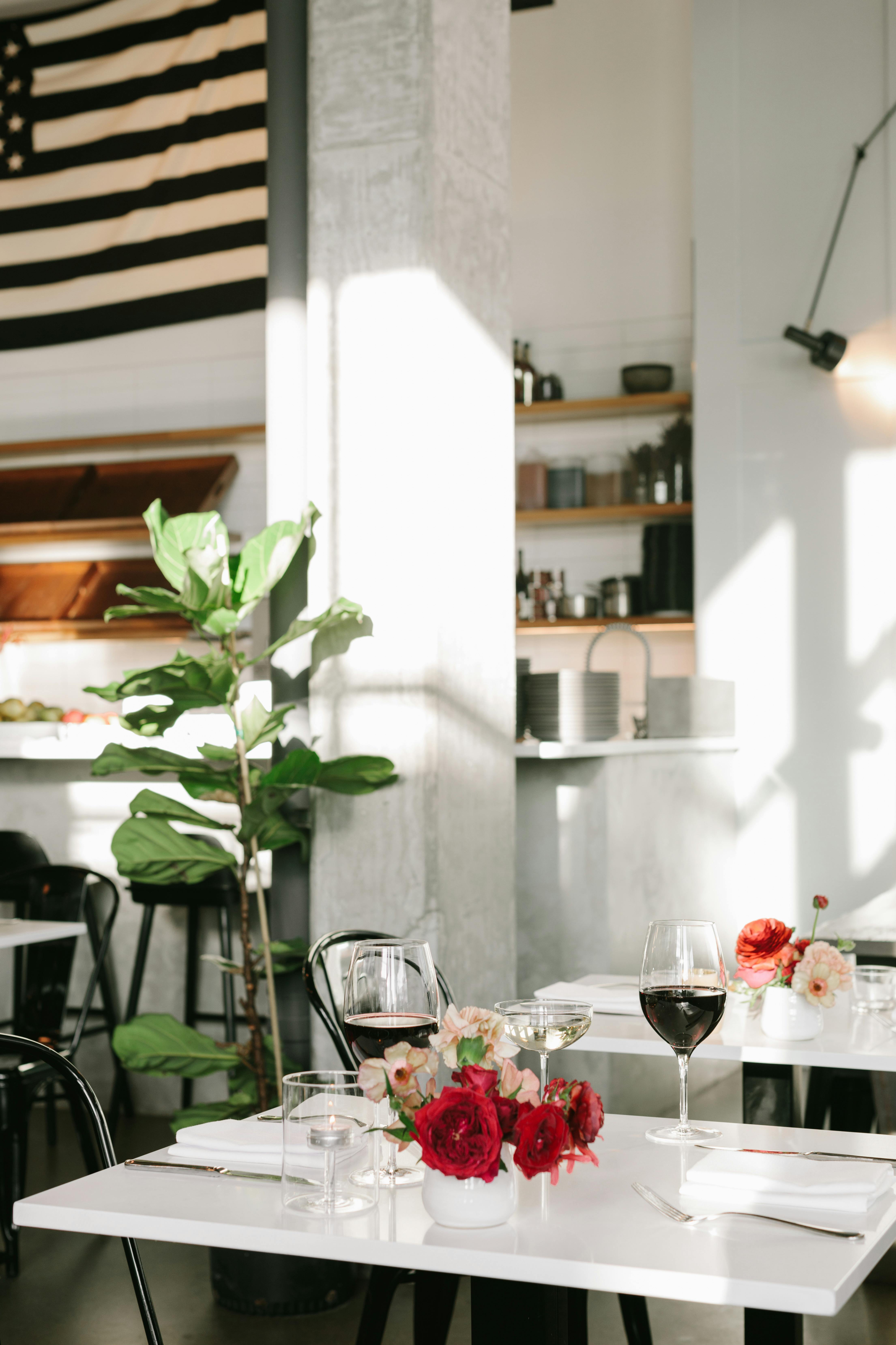 Sophisticated restaurant interior featuring wine glasses, floral decor, and natural light. Perfect for intimate meals.