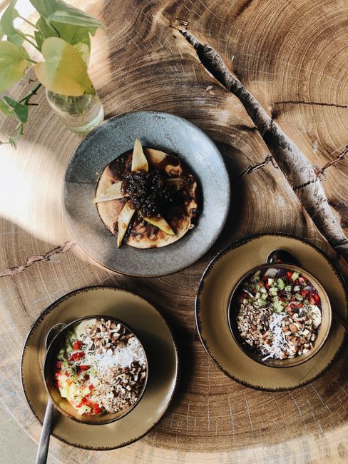 Flat lay of delicious breakfast bowls and pancakes on a wooden table in Tulum, Mexico.