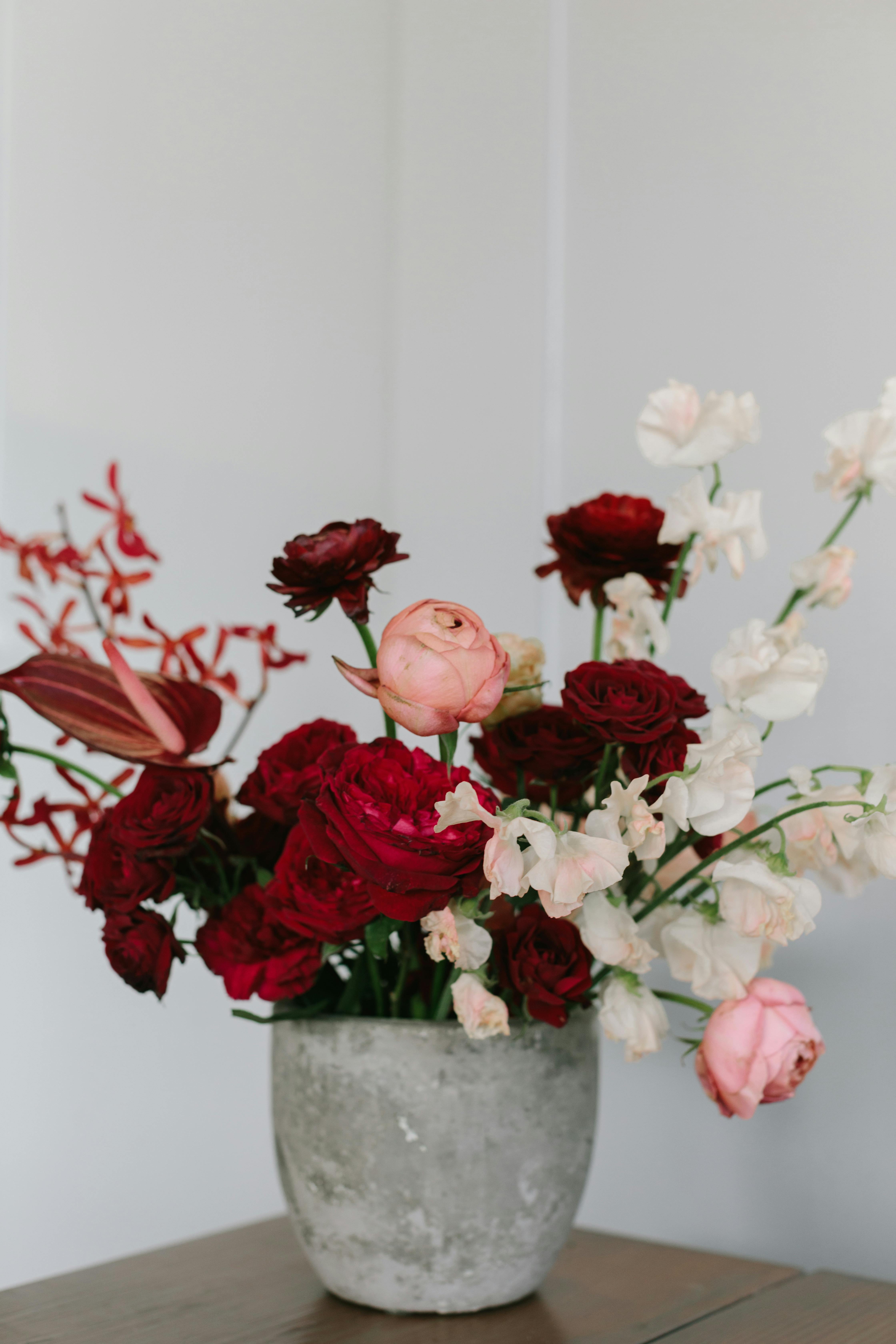 A beautiful floral arrangement featuring red roses and pink peonies in a simple vase, perfect for decor.