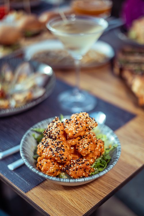 Free Asian sesame chicken served with a martini in a cozy restaurant setting. Stock Photo