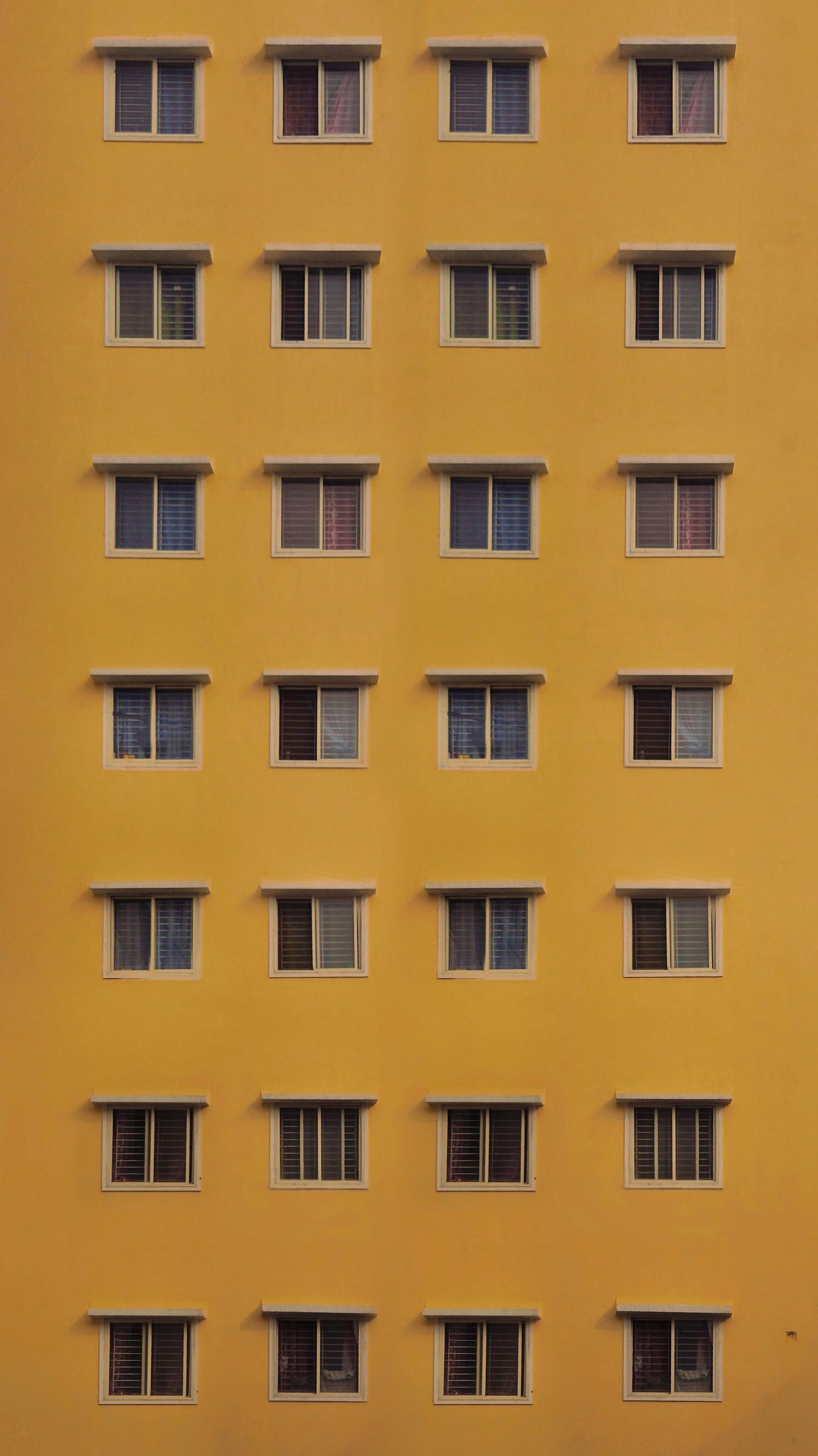 An architectural facade with rows of windows on a bright yellow building.