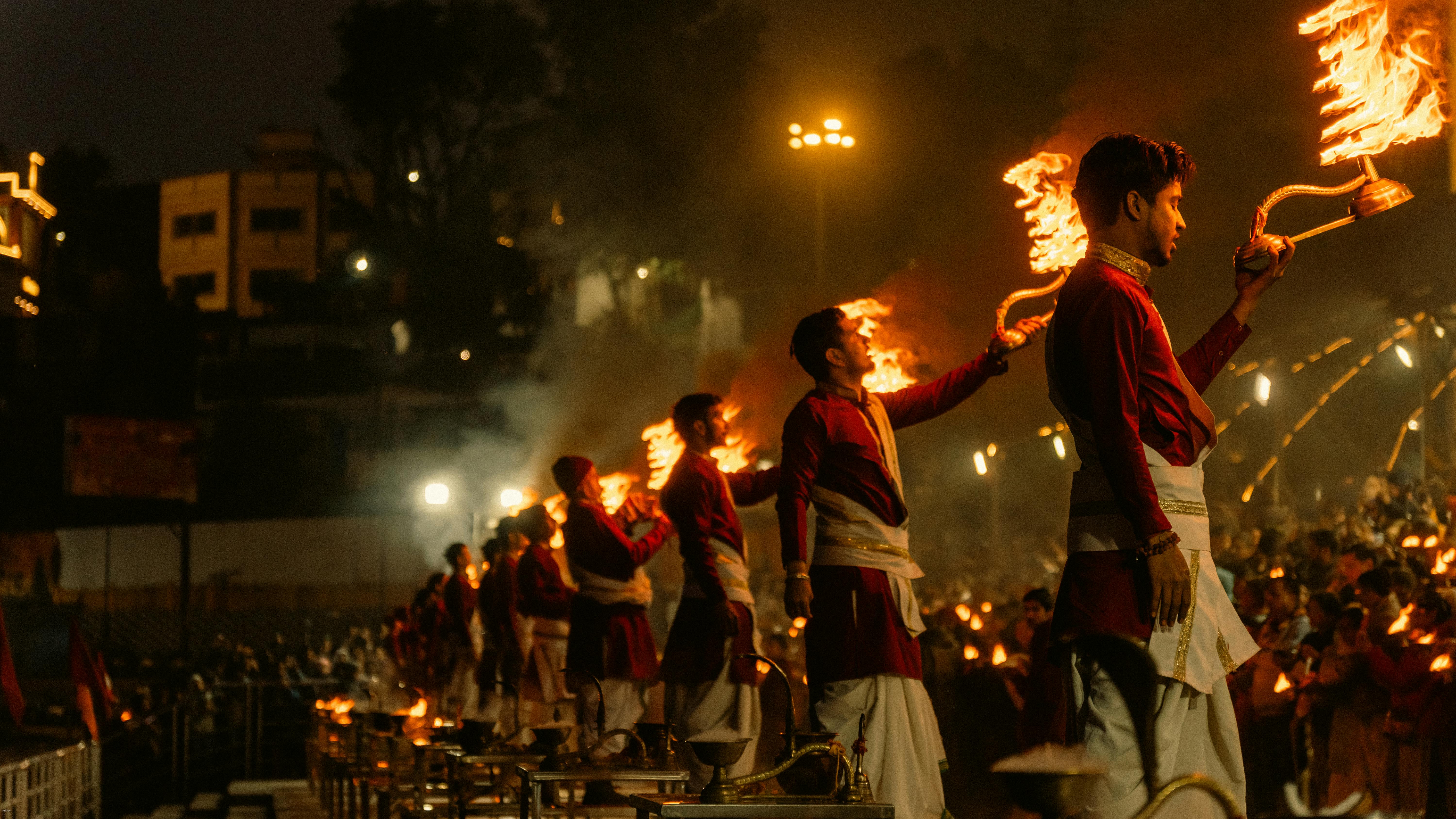 Captivating Ganga Aarti ceremony in Rishikesh, India with priests holding flaming torches.