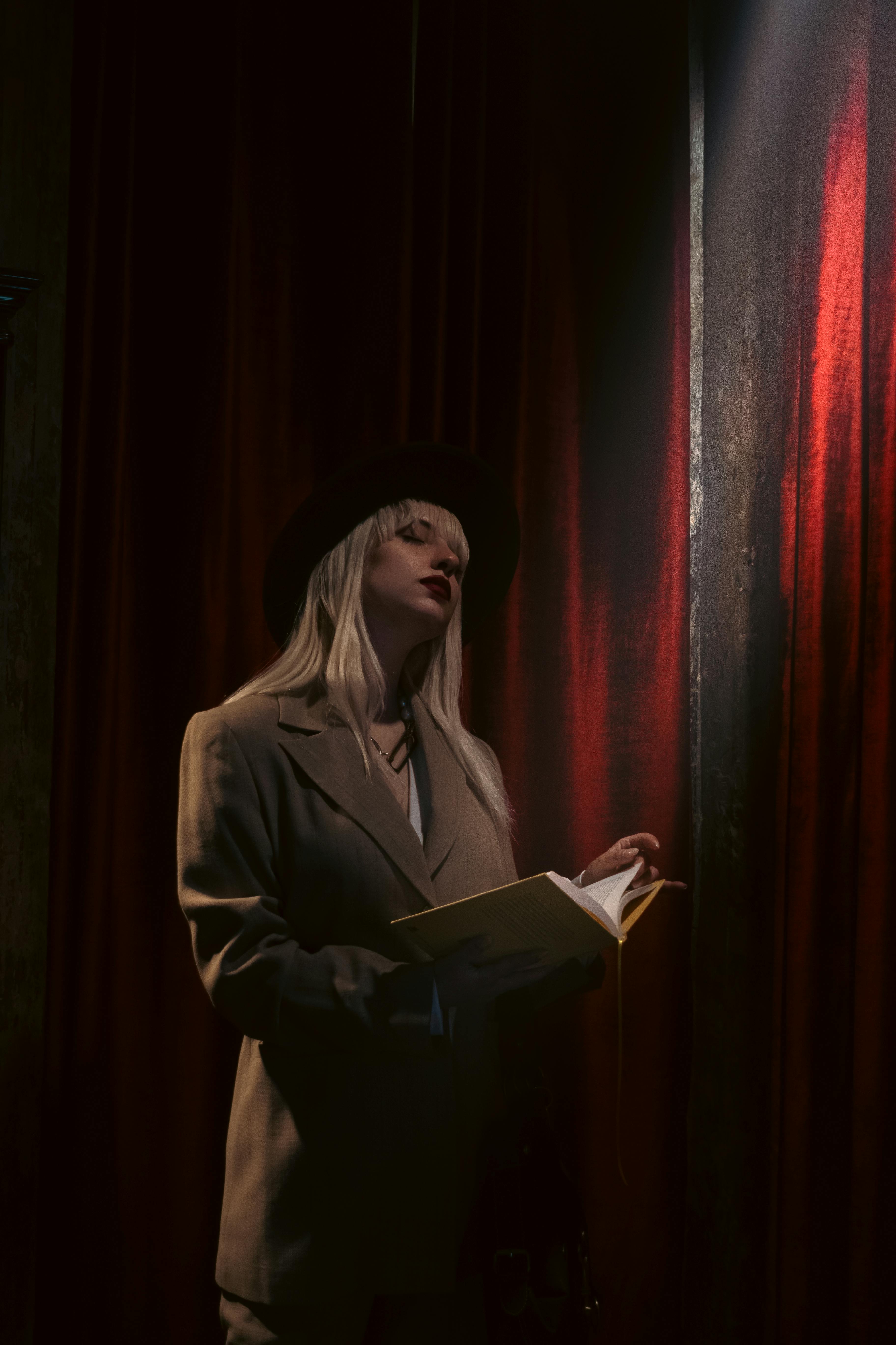 無料 ドラマチックな照明の下で本を持つスーツを着た女性 写真素材