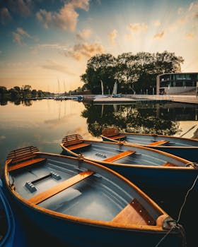 在充满活力的日落时分，一艘划艇停泊在宁静的湖边码头，倒影映在平静的水面上