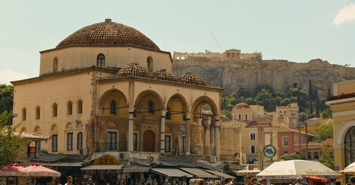 Bustling Monastiraki Square in Athens with the iconic Acropolis in the background.