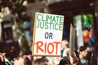 在一场关注气候变化的街头集会上，特写镜头里的抗议标语写着“气候正义或骚乱”