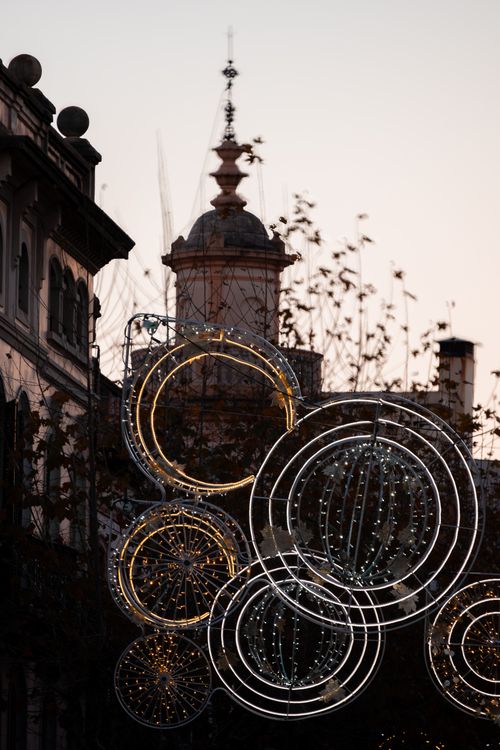 Free Decorative circular lights adorn a European cityscape during twilight. Stock Photo