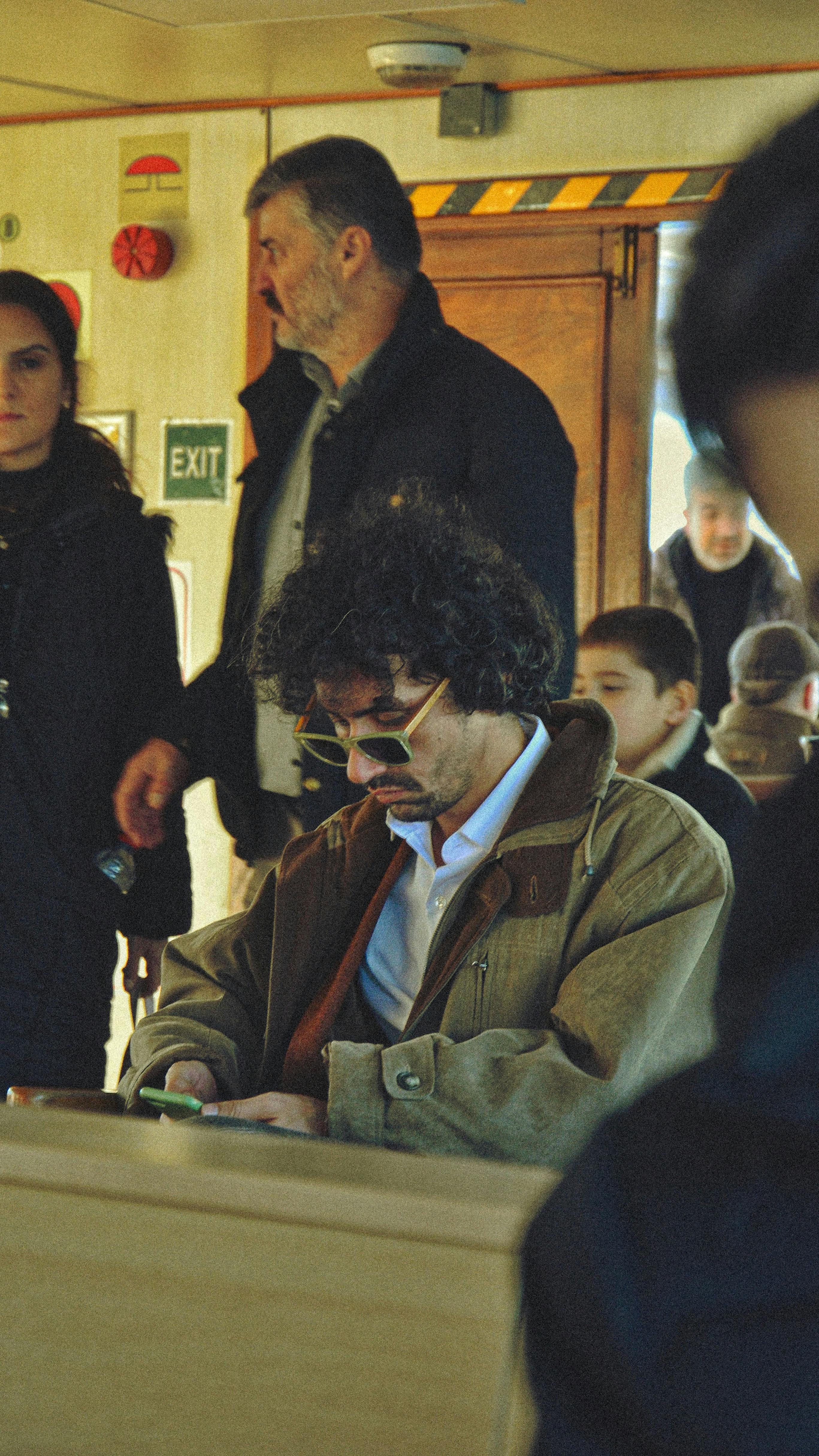 A candid shot inside a transit area with people of different ages engaged in various activities.