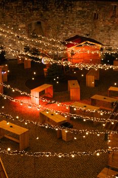 Charming outdoor market scene with glowing string lights on a cobblestone street during nighttime.