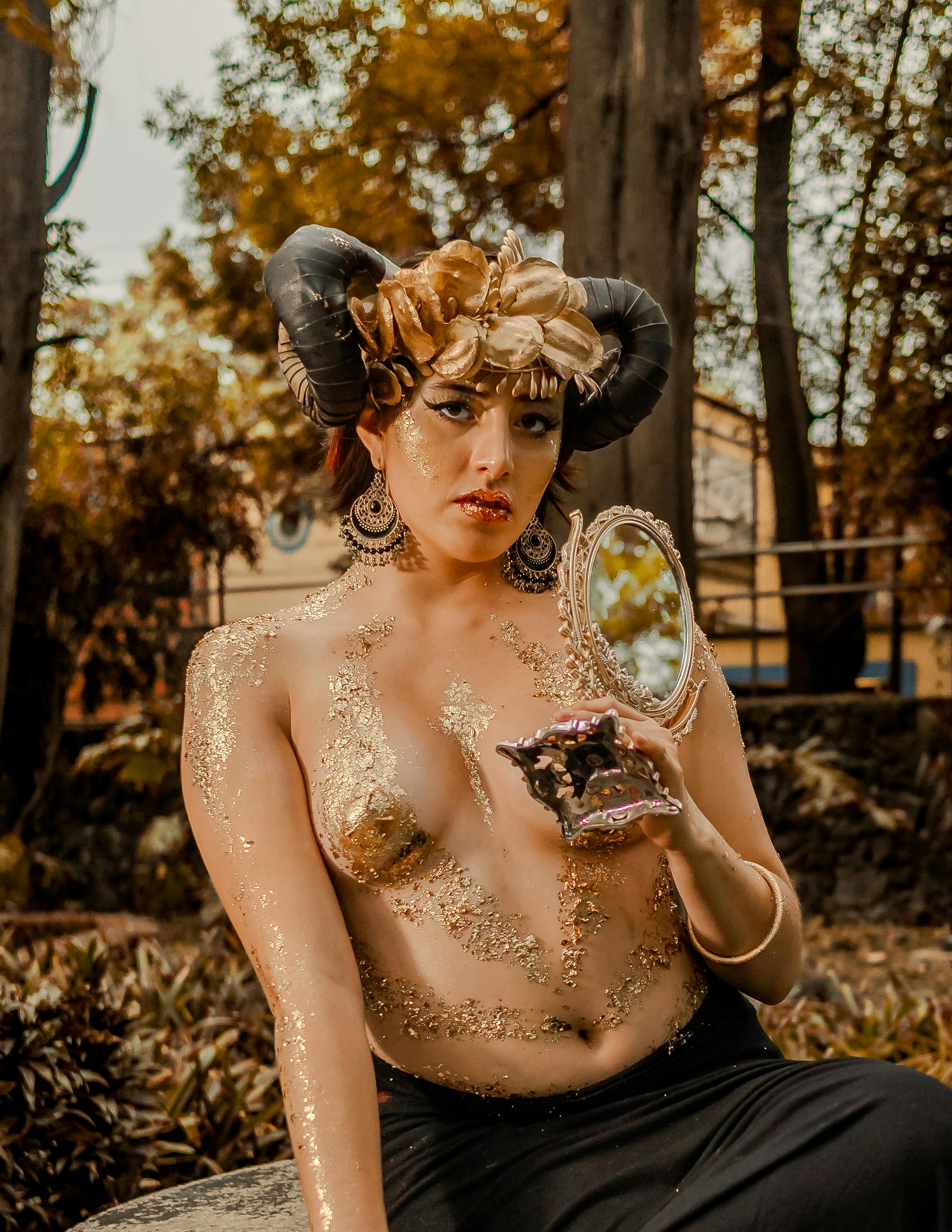 Gratuit Portrait mystique d'une femme avec un maquillage artistique et une coiffe à cornes tenant un miroir dans un décor surréaliste. Photos