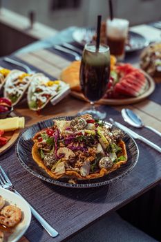 A colorful and diverse platter featuring Middle Eastern salad and beverages on a rooftop restaurant table in Baghdad.