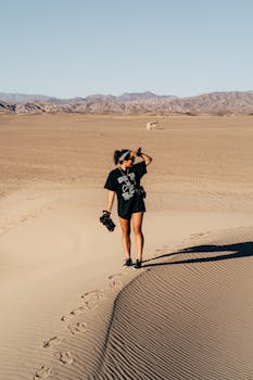 一位孤独的女子在广袤沙漠中翻越沙丘，拥抱冒险