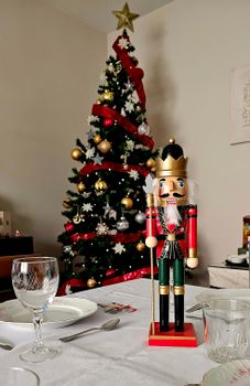 Christmas table setting with a festive nutcracker and decorated tree in the background.