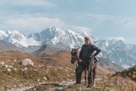一名男子牵着马，站在令人惊叹的雪山背景前